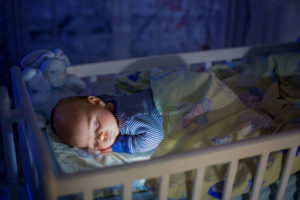 Baby sleeping in his crib at night with the lights off