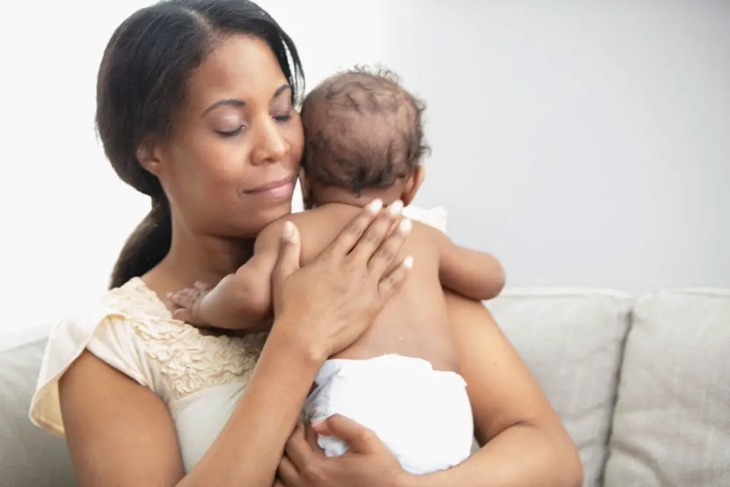 African American Mother holding her baby who is wearing a diaper